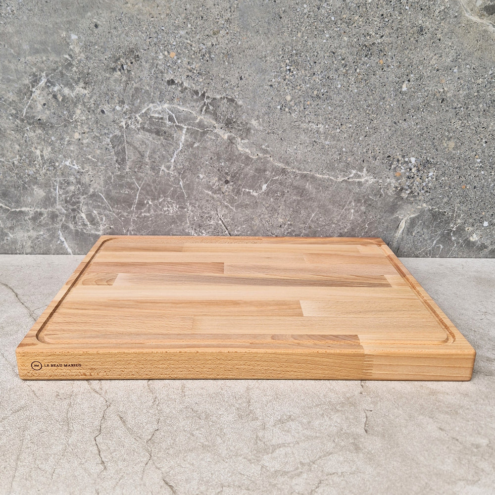 Planche en hêtre massif 52×38 cm avec rainure à jus sur un plan de travail en marbre