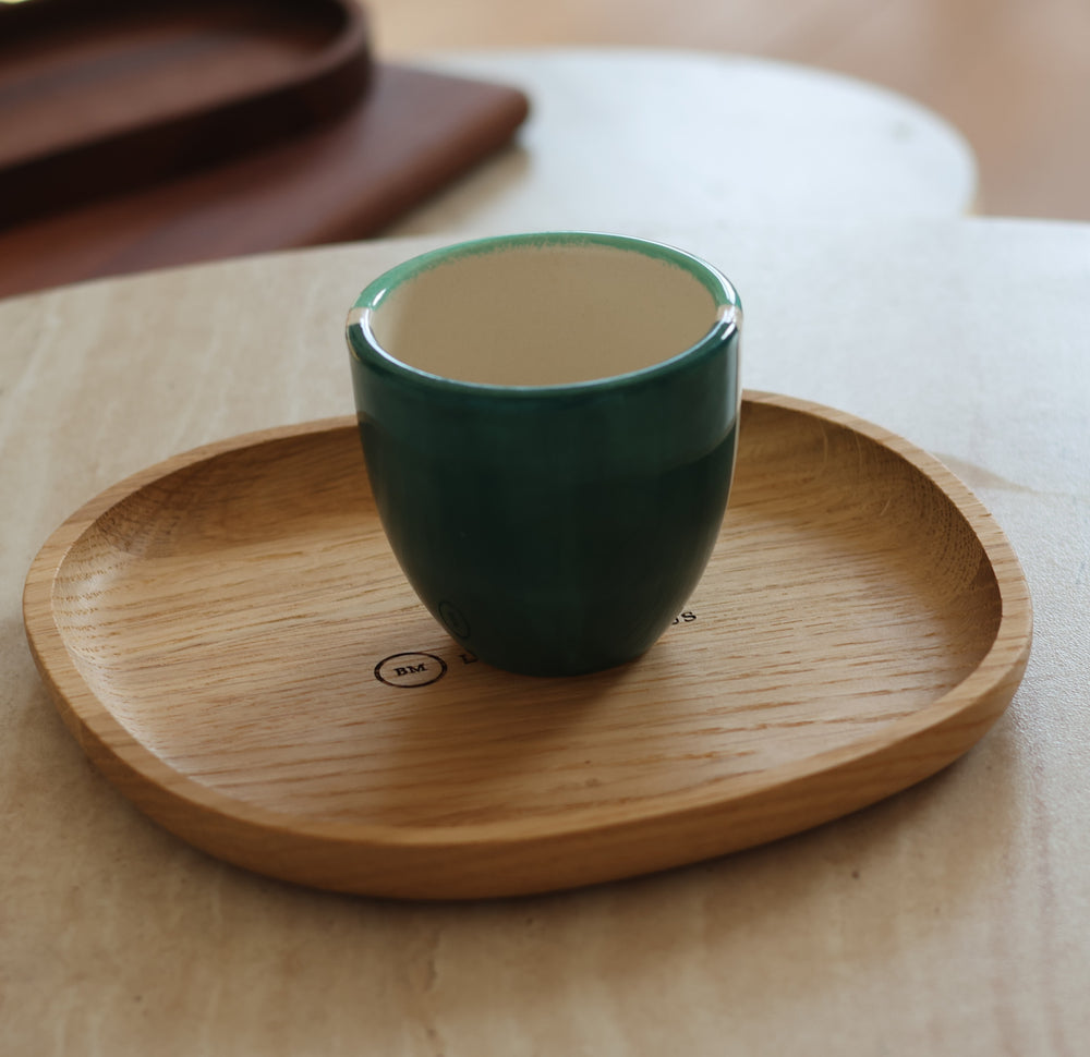Tasse en céramique verte posée dans le vide-poche galet en chêne massif